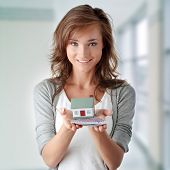 stock photo of investment  - Beautiful young woman holding euros bills and house model over white  - JPG 