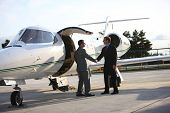 picture of businessmen  - Businessmen shake hands by corporate jet - JPG 