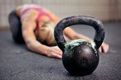 pic of health  - Young woman stretching her back after a heavy kettlebell workout in a gym - JPG 