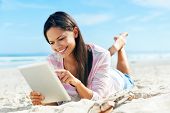 foto of internet  - carefree woman uses touchpad tablet technology on the beach with internet vacation - JPG 