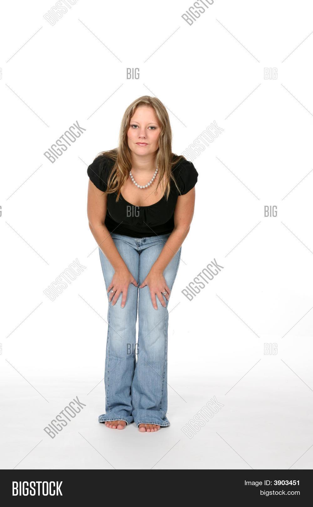 Pretty Young Woman Leaning Forward With Hands On Thighs Stock Photo