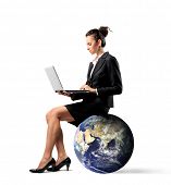 stock photo of earth  - Businesswoman sitting on the earth and using a laptop - JPG 