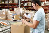 stock photo of computer  - Worker Using Tablet Computer In Distribution Warehouse - JPG 