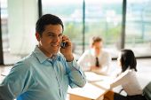 pic of meeting  - A latino male answers a phone call during a business meeting with his colleagues - JPG 
