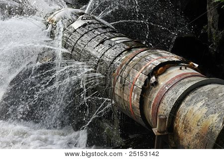 Picture or Photo of A broken pipe that leaks water in all directions.