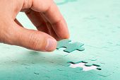 foto of insert  - Hand inserting missing piece of green jigsaw puzzle into the hole - JPG 