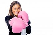 stock photo of competition  - Successful competitive businesswoman is happy and and has boxing gloves while wearing a suit and isolated on white background - JPG 
