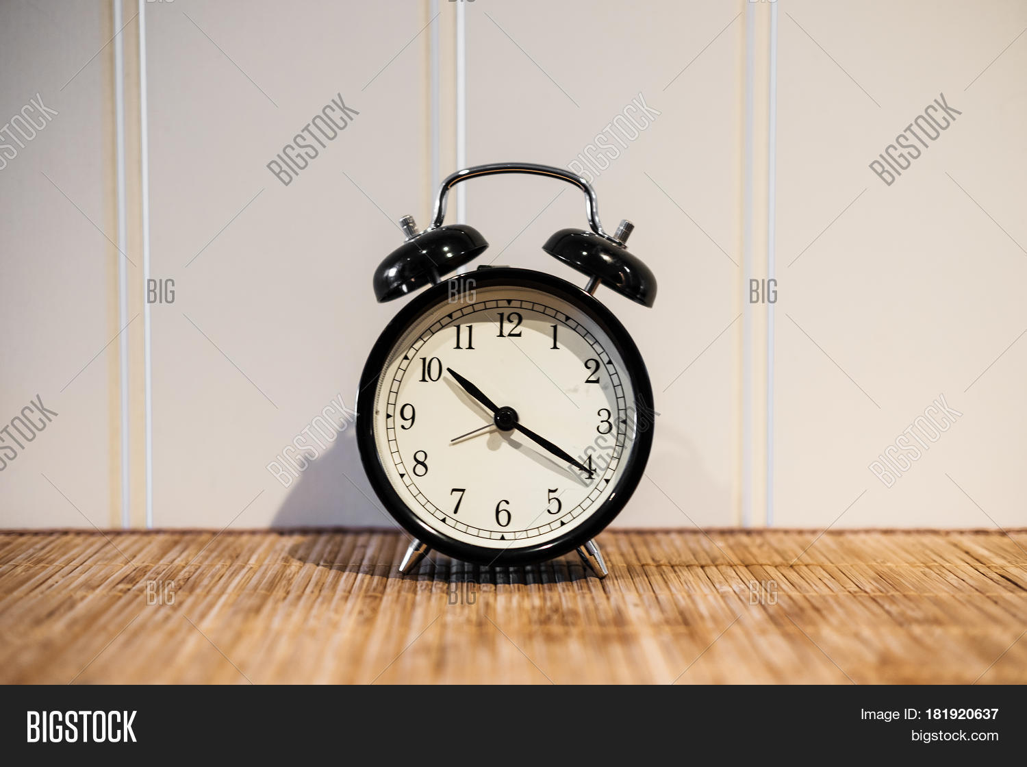 Alarm clock with 10 O'clock and twenty minuet, on wooden table and