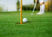 image of golf  - Golf ball and female golfer in background - JPG 