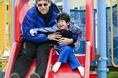 pic of cerebral  - Father going down slide with disabled son who has cerebral palsy - JPG 