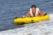 picture of wake  - Teenage sliding across boat wake in inner tube with a great look of effort on his face - JPG 