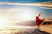 image of sunset  - Image of female ballet dancer against sunset background soaring above water waves - JPG 