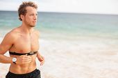 picture of fitness  - Runner man running with heart rate monitor on beach topless - JPG 