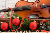 picture of holidays  - A violin and sheet music sits on a piano that has been decorated for the Christmas holiday - JPG 