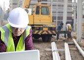 picture of construction  - foreman construction site using laptop with construction background and worker - JPG 