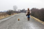 picture of dog  - Senior woman walking her dog on an overcast winter day - JPG 