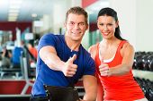 stock photo of fitness  - Woman with her personal fitness trainer in the gym exercising with dumbbells - JPG 