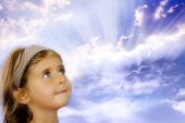 image of curiosity  - small girl looking at divine rays of light with expression of curiosity - JPG 
