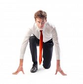 stock photo of competition  - Isolated young businessman kneeling as if about to start a race - JPG 
