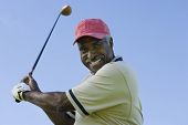 picture of golf  - Portrait of a happy senior man swinging a golf club against clear sky - JPG 