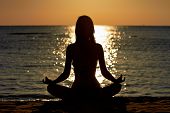 stock photo of nature  - Silhouette of woman in yoga lotus meditation position front to seaside - JPG 