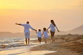 foto of beach  - happy young family have fun on beach run and jump  at sunset - JPG 