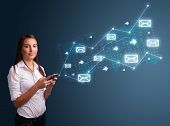 picture of standing  - Attractive young lady standing and holding a phone with arrows and message icons - JPG 