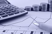 stock photo of finance  - Economic graph with culculator pen and coins - JPG 
