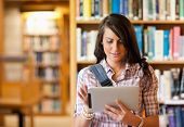 foto of technology  - Cute young student using a tablet computer in a library - JPG 