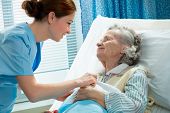 picture of home  - Nurse cares for a elderly woman lying in bed - JPG 