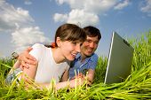 picture of computer technology  - Happy couple on a laptop computer outdoors - JPG 