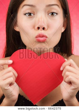 Cute Valentines Day Woman Kiss. Valentines day kiss? Woman blowing a kiss holding a Valentines Day heart sign. Beautiful mixed race chinese / caucasian 