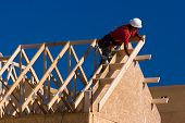 pic of construction  - Carpenter with red shirt and white hardhat building a roof of a house at a construction site - JPG 