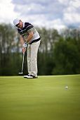stock photo of golf  - Senior male golf player putting a golf ball on the green - JPG 