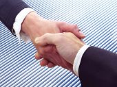stock photo of handshake  - Conceptual photography of a business handshake on a blue background - JPG 