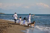 image of animals  - happy young family in white clothing have fun and play with dog on vacation on a beautiful beach - JPG 