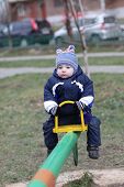 foto of seesaw  - The pensive toddler is swinging on seesaw - JPG 