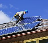 stock photo of man  - Man installing alternative energy photovoltaic solar panels on roof - JPG 