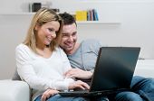 image of laptop  - Young couple relaxing on the couch with laptop in their living room at home - JPG 