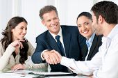 picture of meeting  - Mature businessman shaking hands to seal a deal with his partner and colleagues in a modern office - JPG 