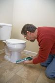 pic of seep  - Contractor caulking around toilet to keep moisture from seeping - JPG 