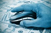 image of fraud  - a hand man using a computer mouse on a background full of dollar banknotes - JPG 