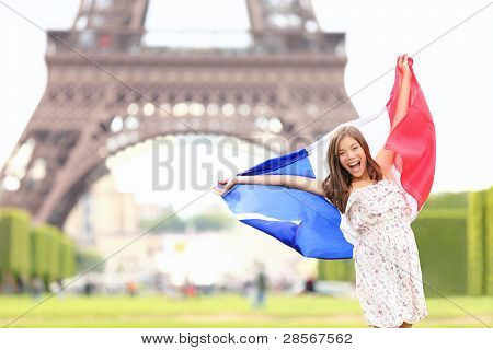 Picture or Photo of France - french flag woman by Eiffel tower Paris. France travel concept with excited and happy young girl holding the French flag.