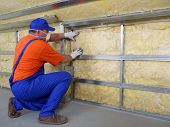 image of construction worker  - Construction worker thermally insulating house attic with mineral wool - JPG 