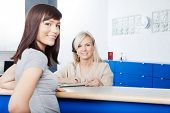 stock photo of receptionist  - Portrait of young woman with receptionist filling form at desk in dentist - JPG 