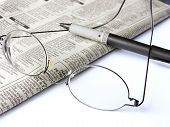 foto of newspaper  - a pair of reading glasses and pen laying across a folded newspaper - JPG 
