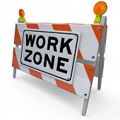 picture of construction  - An orange and white construction barricade sign blocking an area that is a designated work zone where workers are improving a road - JPG 