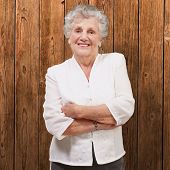 foto of standing  - portrait of an adorable senior woman standing against a wooden wall - JPG 