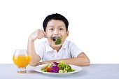 stock photo of boy  - Boy is eating broccoli and salad on white background - JPG 