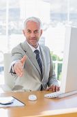foto of handshake  - Smiling businessman reaching out for handshake at his desk - JPG 